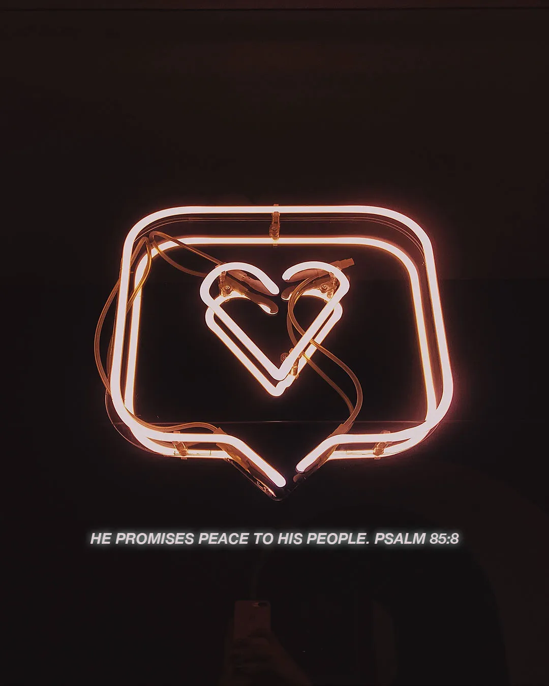 Experimental church media featuring a glowing neon message icon with heart symbol and Psalm 85:8 "He promises peace to His people" on black background