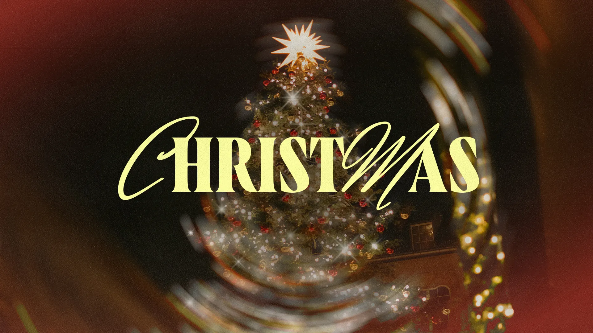 The word Christmas in cream script over a blurred, glowing Christmas tree with a gold star and red lights