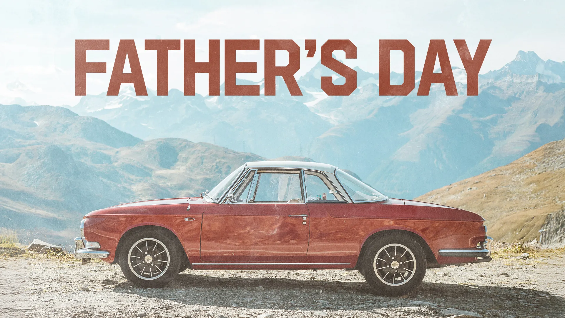 Classic red car parked against a scenic mountain backdrop, promoting Father's Day celebration at the church.