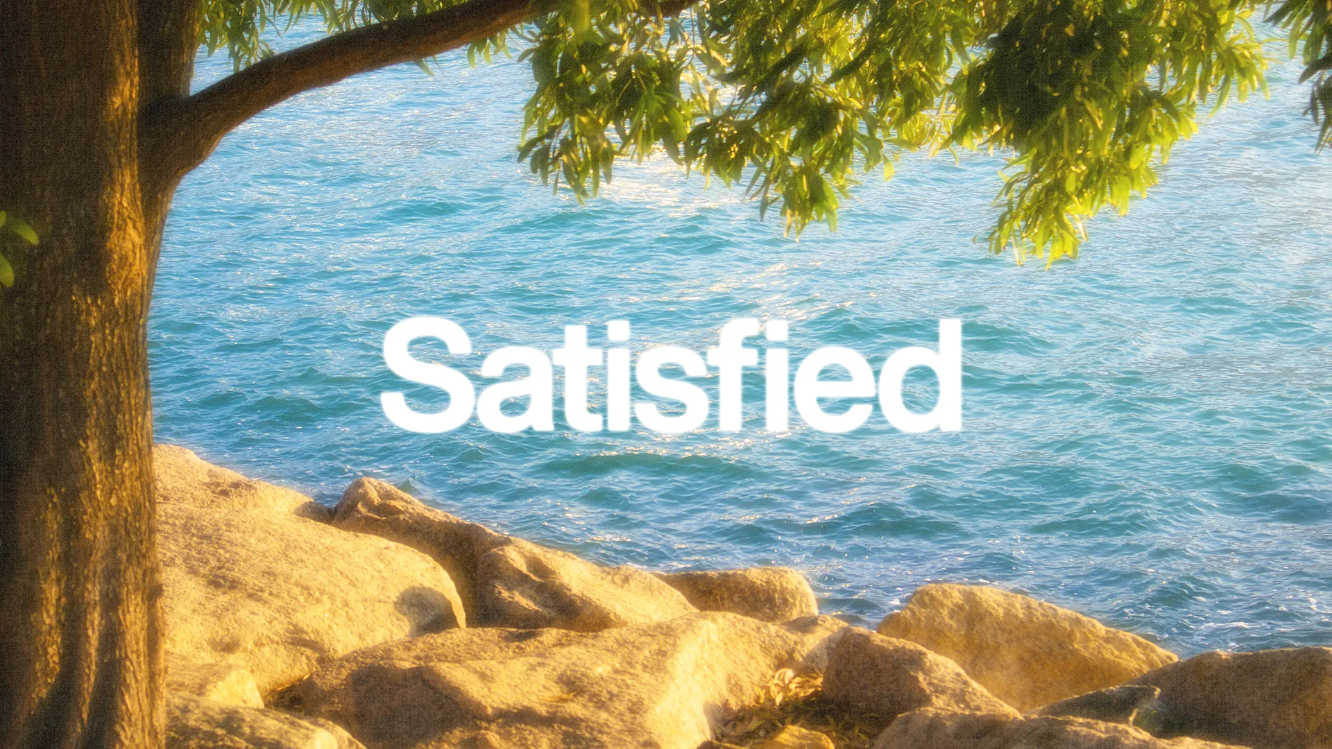 Tranquil waters and rocks beneath a tree, with the word "Satisfied" symbolizing faith and spiritual fulfillment.